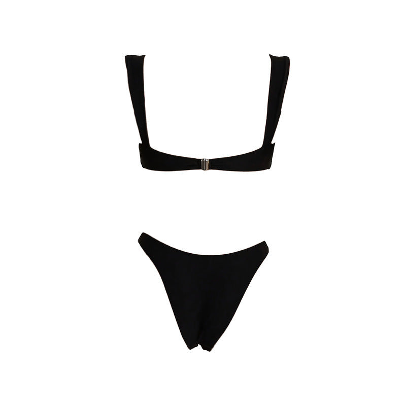 Dammodell bär lyxig svart bikini med guldaccent på en solig strand, perfekt för sommar och badkläder.