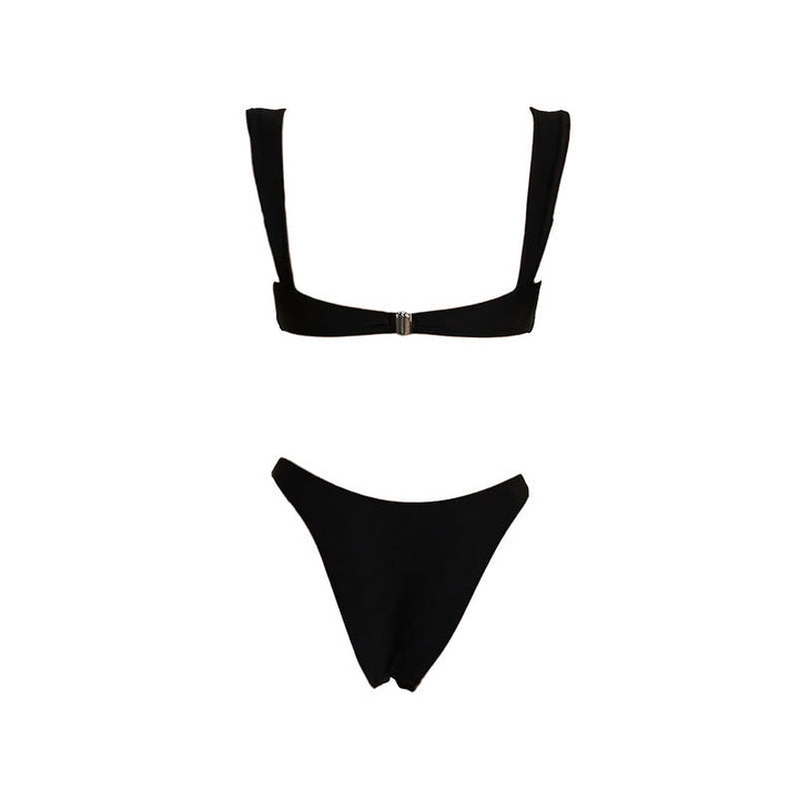 Dammodell bär lyxig svart bikini med guldaccent på en solig strand, perfekt för sommar och badkläder.