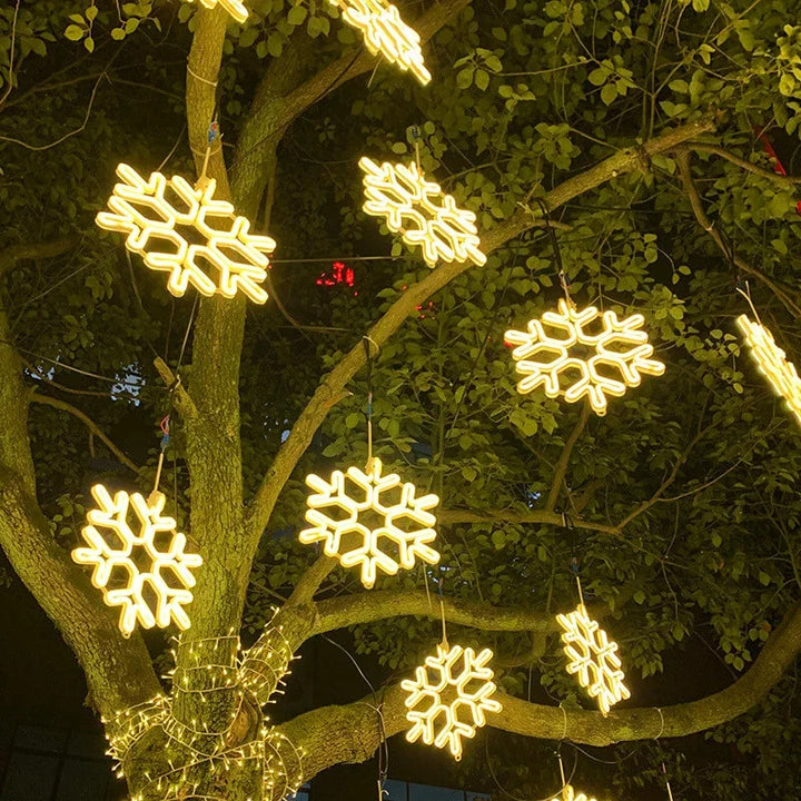 Närbild på lysande snöflingeformad julbelysning i grenverk