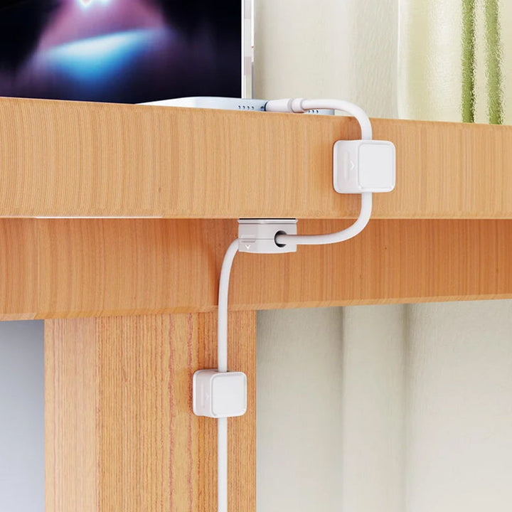 "Magnetisk kabelhållare håller kablar organiserade, stilren design i svart och vit, passar kablar upp till 7 mm."