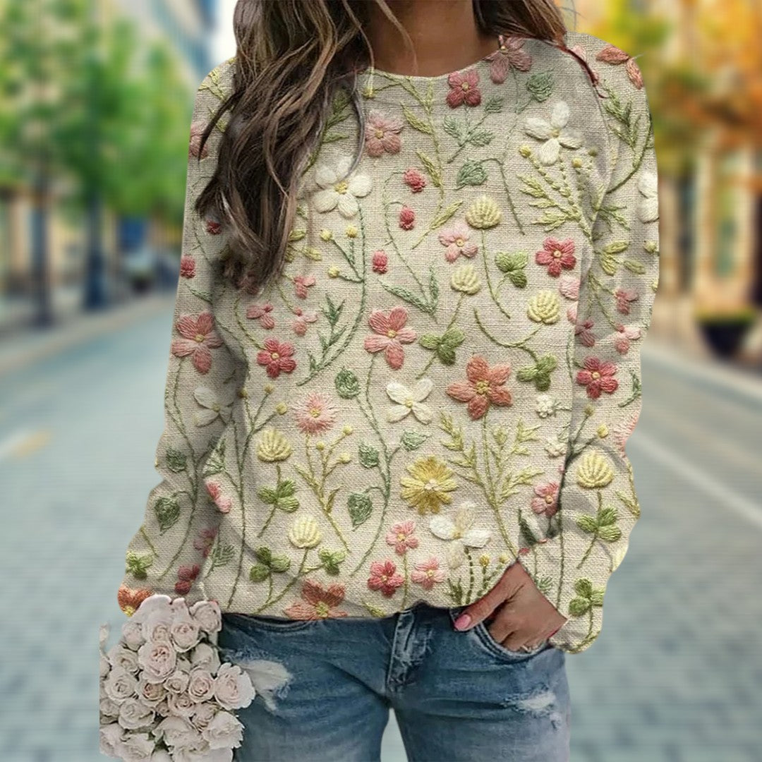 Närbild på damtröja med detaljerat blommönster och långa ärmar