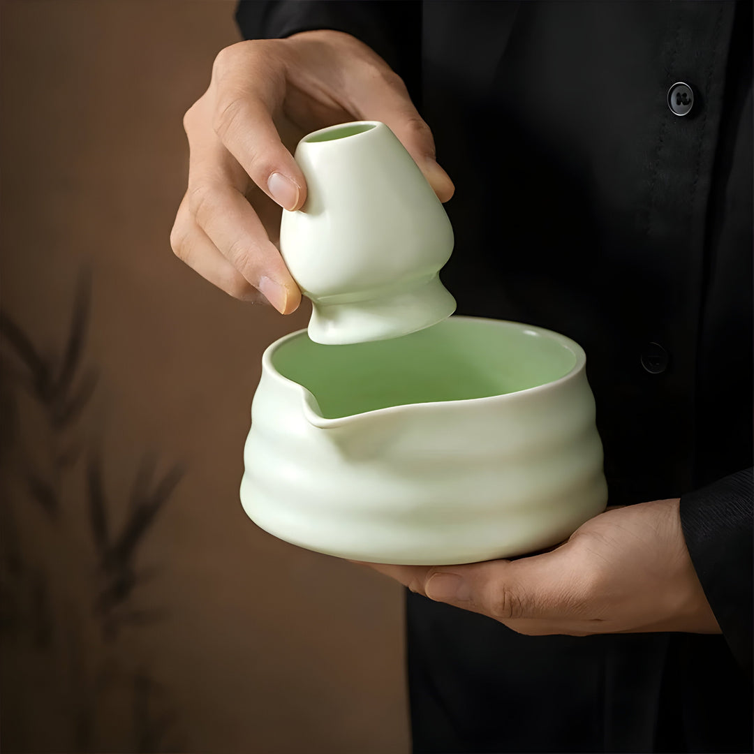 Traditionell grön matcha i keramisk skål bredvid bambuvisp och skopa