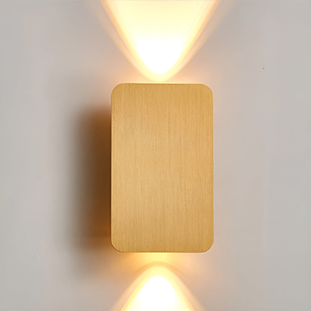 Stilren guld-färgad LED-vägglampa som sprider ett varmt sken på väggen