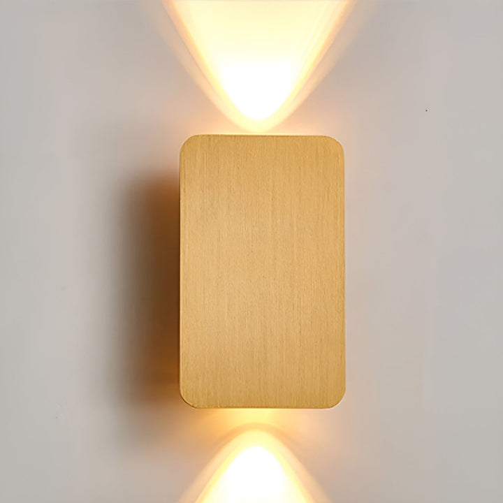 Stilren guld-färgad LED-vägglampa som sprider ett varmt sken på väggen