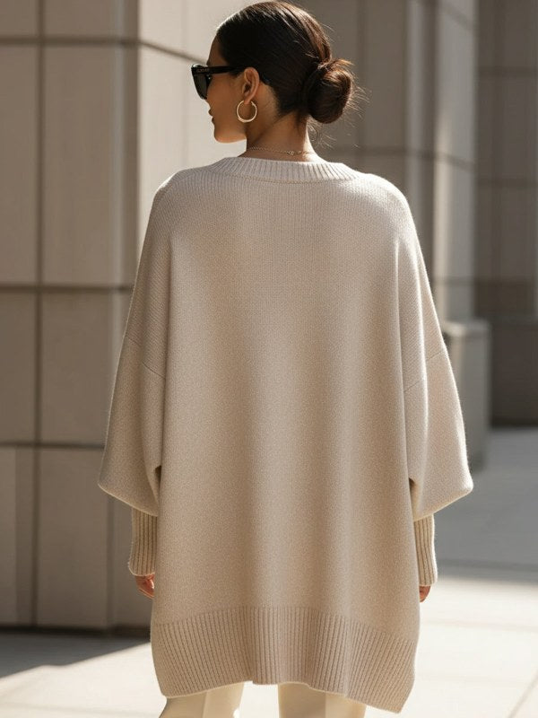 Modell bär bekväm, oversize stickad damponcho-tröja i stilren design. Idealisk för vår och höst.