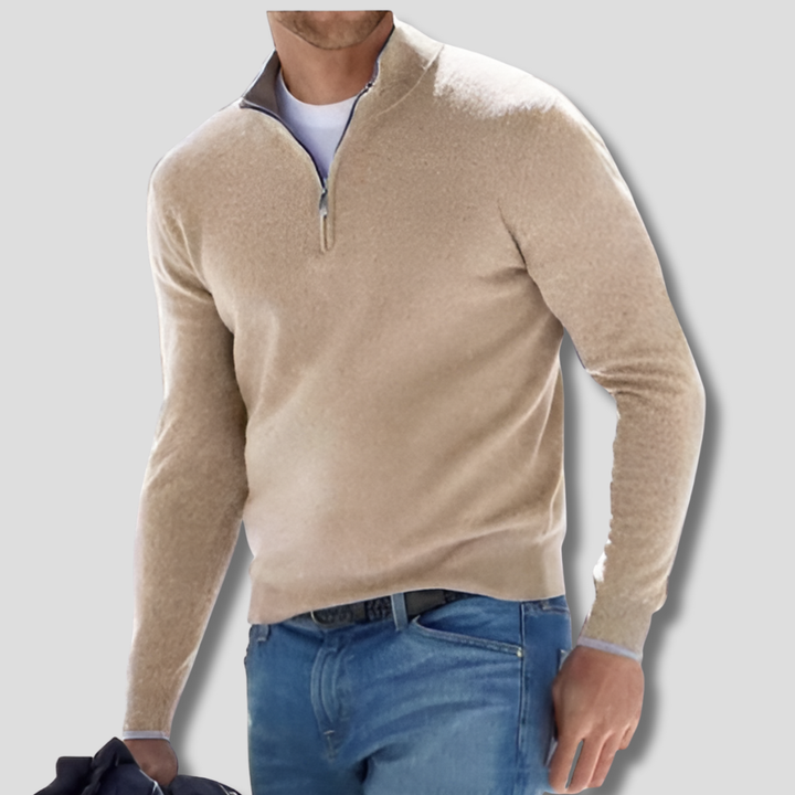 Man bär beige stickad herrtröja med dragkedja i kragen och jeans