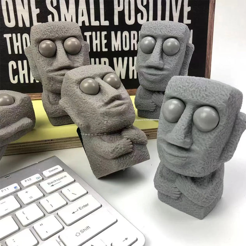 Moai LED stressleksak med utstickande ögon, grå/brun färg, kompakt design, perfekt för stressavlastning och dekoration.