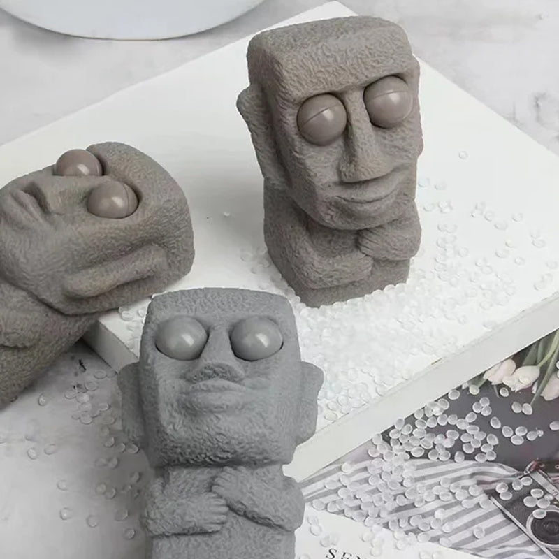 Moai LED stressleksak med utstickande ögon, grå/brun färg, kompakt design, perfekt för stressavlastning och dekoration.