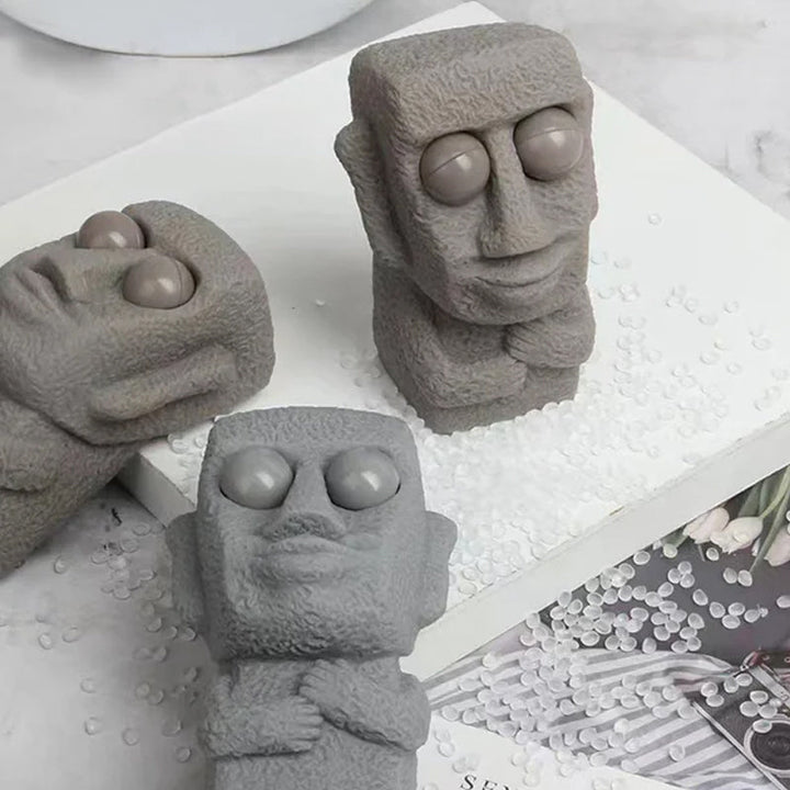 Moai LED stressleksak med utstickande ögon, grå/brun färg, kompakt design, perfekt för stressavlastning och dekoration.