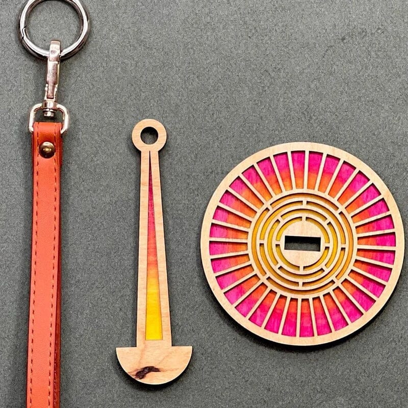 Modern trähållare för garn i minimalistisk design, visar flera garnrullar i olika färger på en stabil träbas.