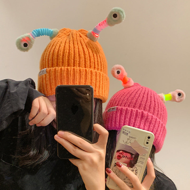 Barn och vuxen monsterstickad mössa i vit med stora justerbara ögon.
