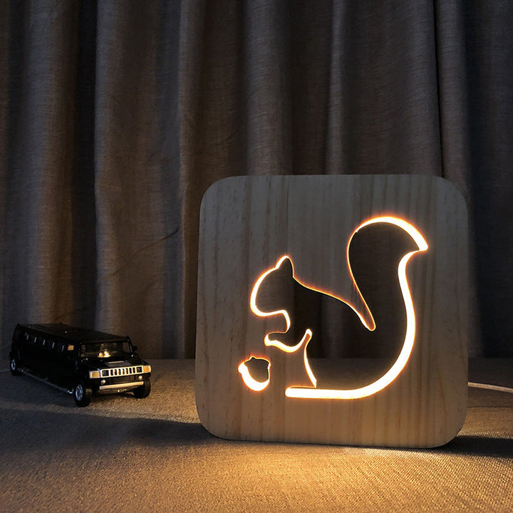 Nattlampa i trä med snidad design, avger varmt sken, perfekt för sovrum eller dekoration.