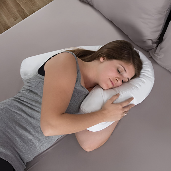 Kvinna som sover bekvämt på sidan med en vit ortopedisk kudde med öronhål