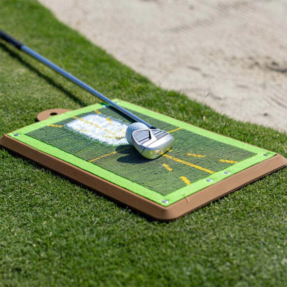 Golfträningsmatta med golfklubba och boll på gräs