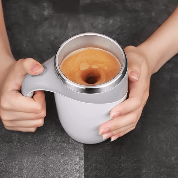 Person som håller i en självrörande magnetisk kaffekopp med nymixad dryck