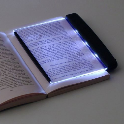 LED boklampa placerad på öppen bok i mörker