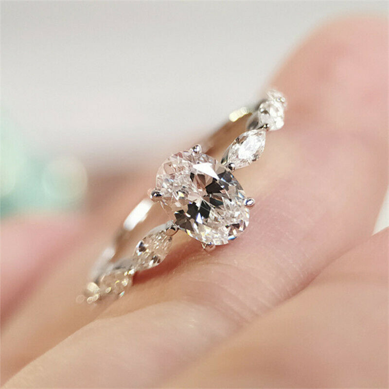 "Oval förlovningsring för damer i silver och guld med moissanite-sten och diamantbesatta band, elegant accessoar."