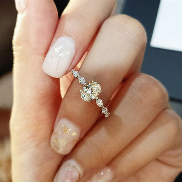 "Oval förlovningsring för damer i silver och guld med moissanite-sten och diamantbesatta band, elegant accessoar."