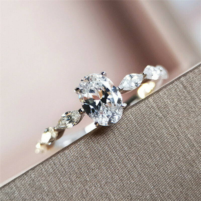 "Oval förlovningsring för damer i silver och guld med moissanite-sten och diamantbesatta band, elegant accessoar."