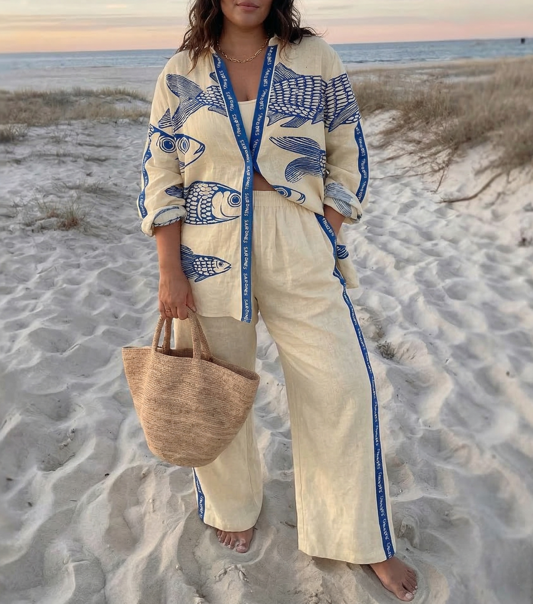 Adair dam linne set i beige med blått fiskmönster på sandstrand