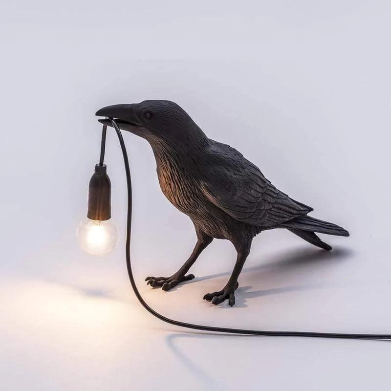 Svart fågellampa som står upp och håller en glödlampa i näbben