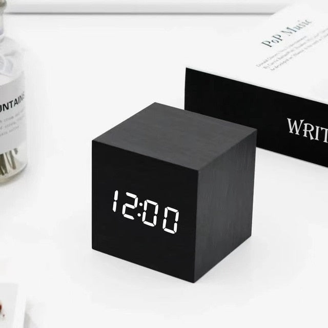 Svart kubformad LED-väckarklocka på ett ljust skrivbord