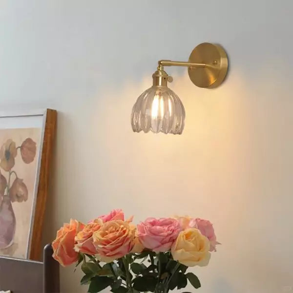 Vägglampa i retrostil med mässingsdetaljer och rosa blommor nedanför