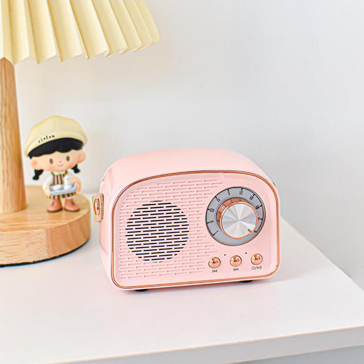 Rosa retro Bluetooth-högtalare på ett skrivbord bredvid en liten lampa