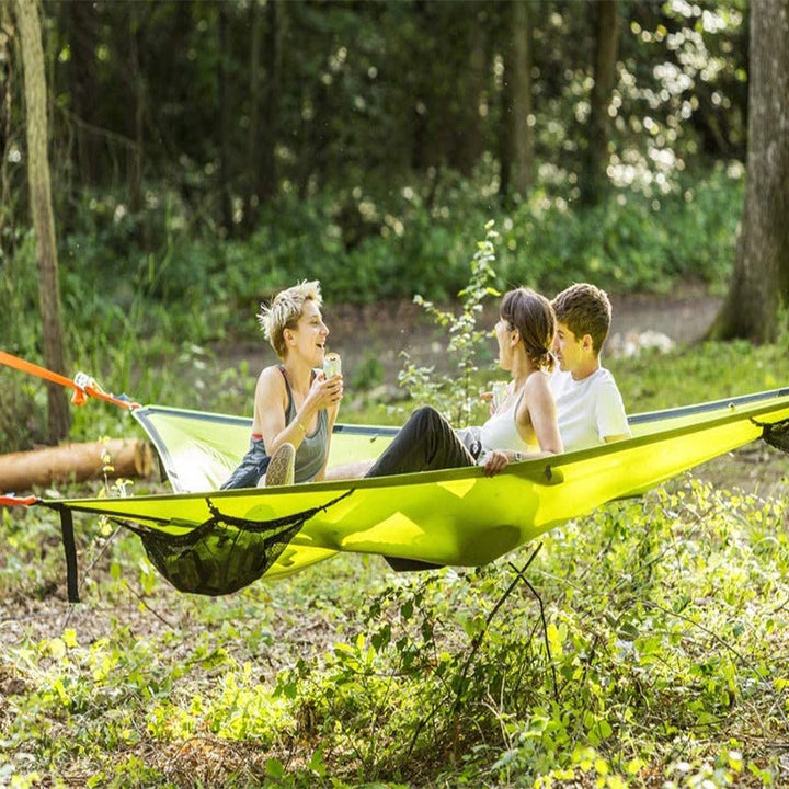 "Robust grön och svart nylonhängmatta för flera personer, perfekt för camping och utflykter, i naturlig miljö."