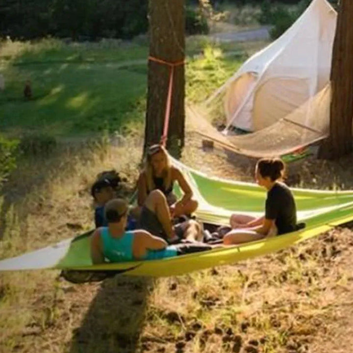 "Robust grön och svart nylonhängmatta för flera personer, perfekt för camping och utflykter, i naturlig miljö."