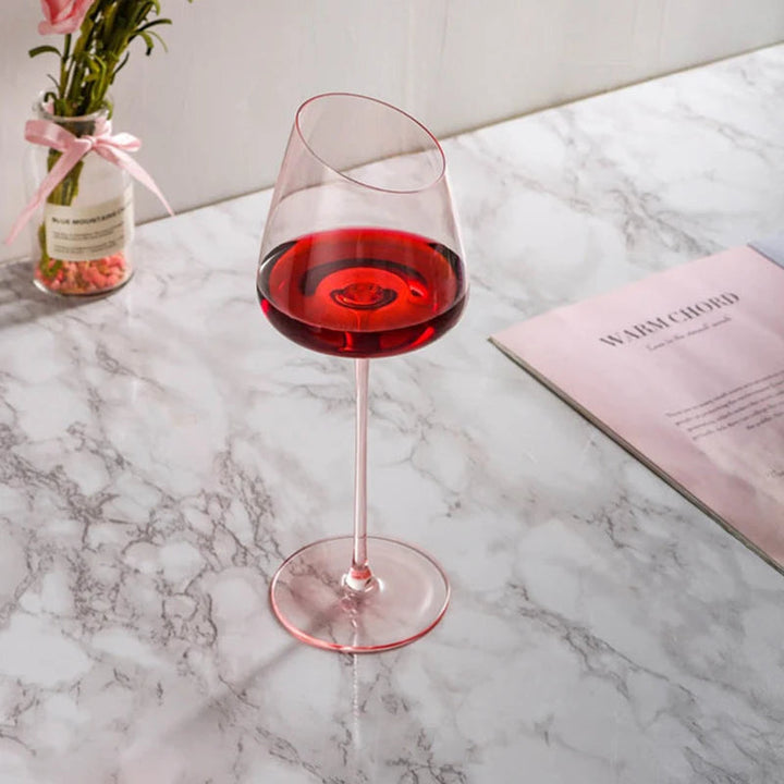 Rosa kristallvinglas fyllda med vin på ett elegant dukat bord. Festliga handblåsta glas.