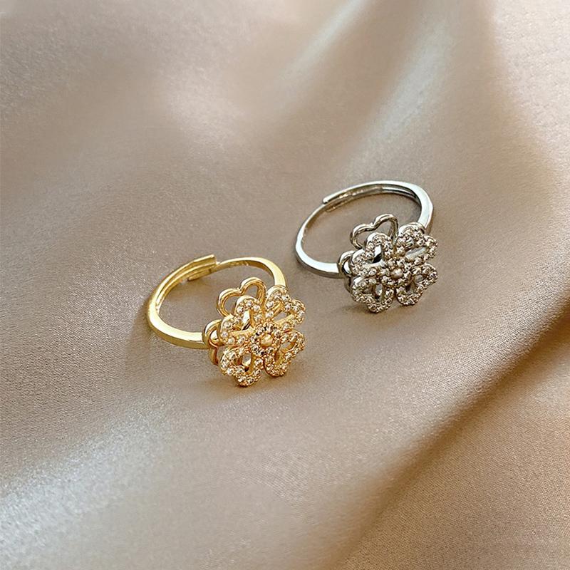 Roterande fyrklöverring för dam i silver eller guld, elegant design med zirkonstenar för modern stil.