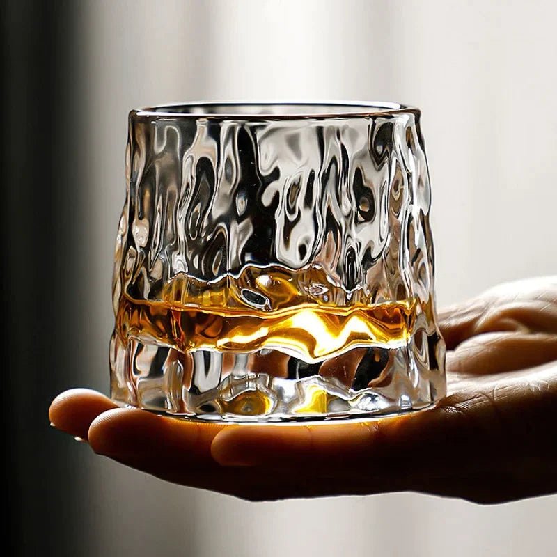 Whiskyglas i kristall fyllt med gyllene sprit, fångar den roterande effekten i rörelse.