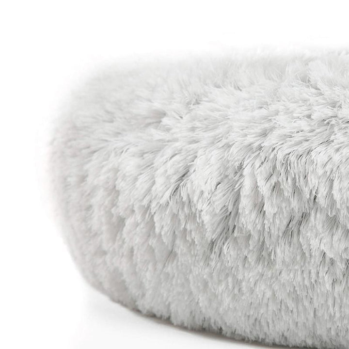 Rund husdjursbädd med mjuk fuskpäls, ljus färg. Designad för små djur, erbjuder lugnande effekt och komfort.