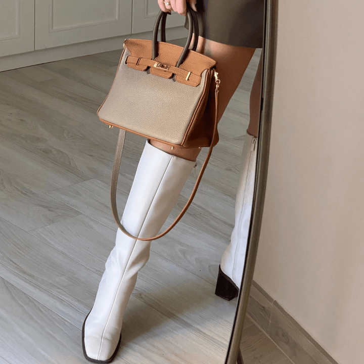 Handväska Élise i beige buren med axelrem mot spegel
