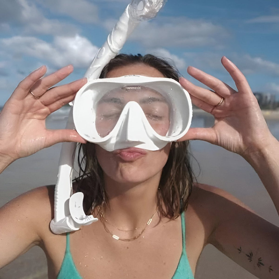 Kvinna som provar vit snorkelmask på stranden