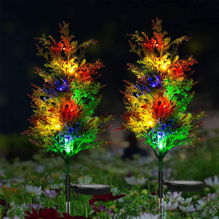 "Solcellsdriven RGB trädgårdsbelysning för jul, naturinspirerad design med cypress- och tallbladseffekt, magisk atmosfär."
