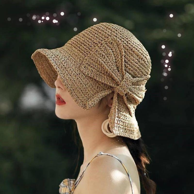Kvinna i profil som bär en elegant beige dam sommarhatt med rosett utomhus.