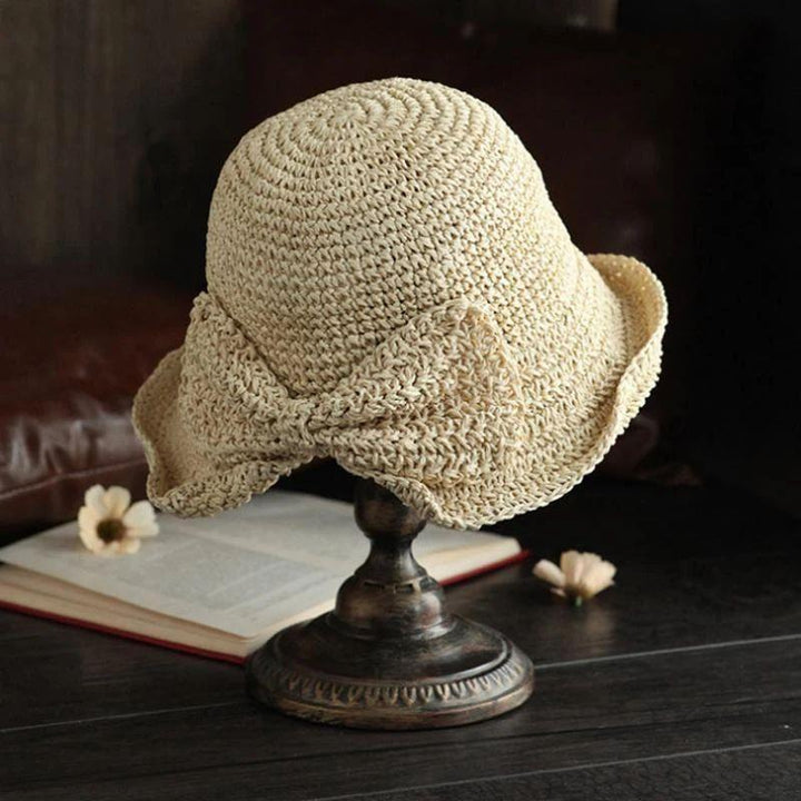 Klassisk sommarhatt i khaki med dekorativ rosett uppställd på skyltdocka.