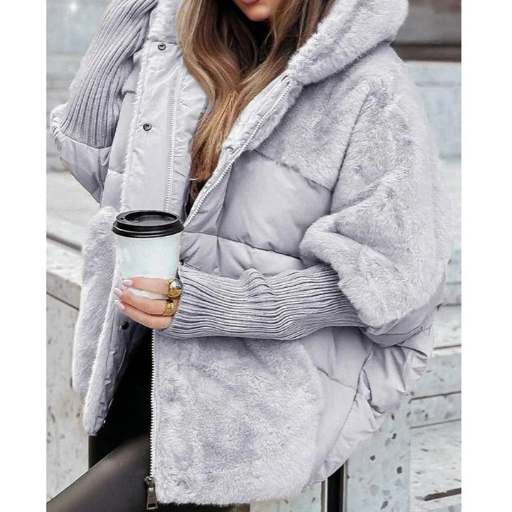 Kvinna i grå damjacka med huva och kaffekopp