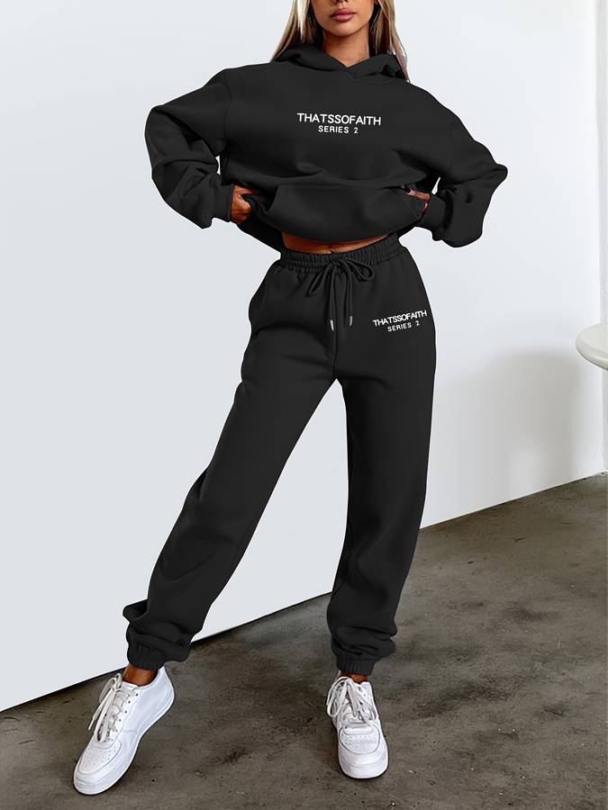 Dammodell i svart stickat athleisure-set med huvtröja och mjukisbyxor utomhus