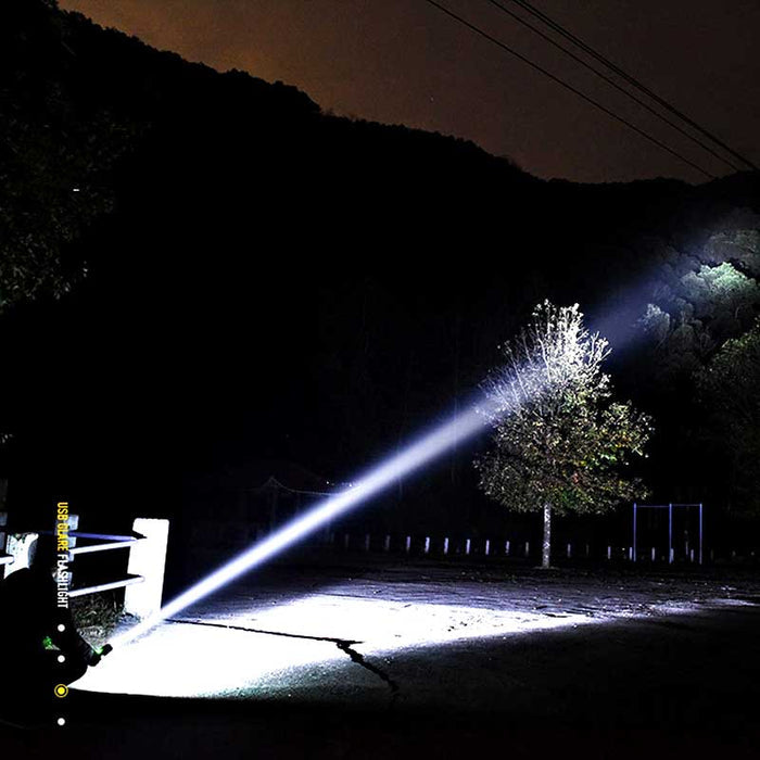 Kraftfull ljusstråle från ficklampan som lyser upp ett mörkt skogslandskap
