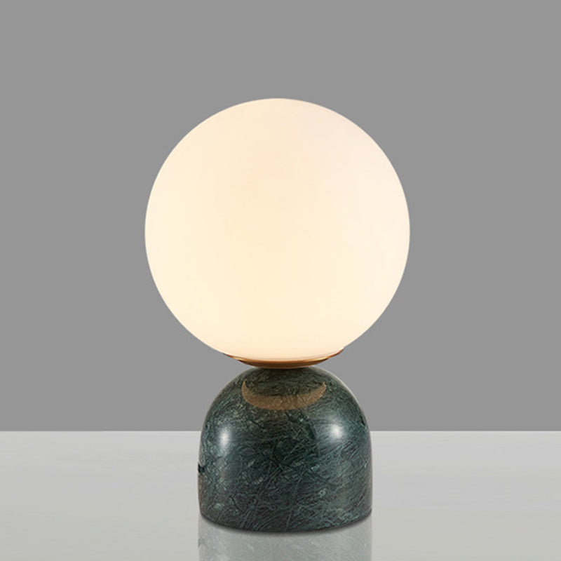 Modern bordslampa med vit glaskula och robust stenfot för snygg heminredning