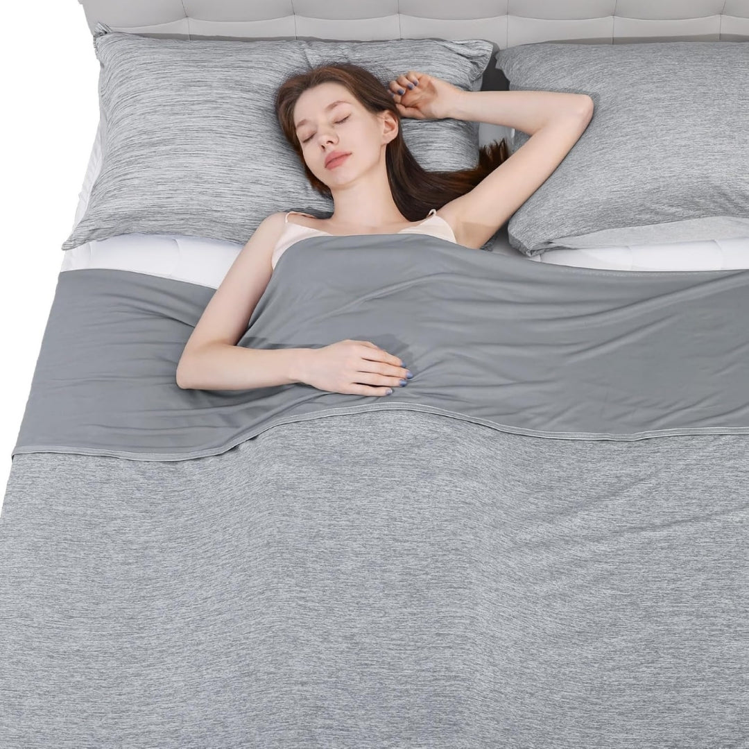 Kvinna som sover gott under en grå svalkande sommarfilt