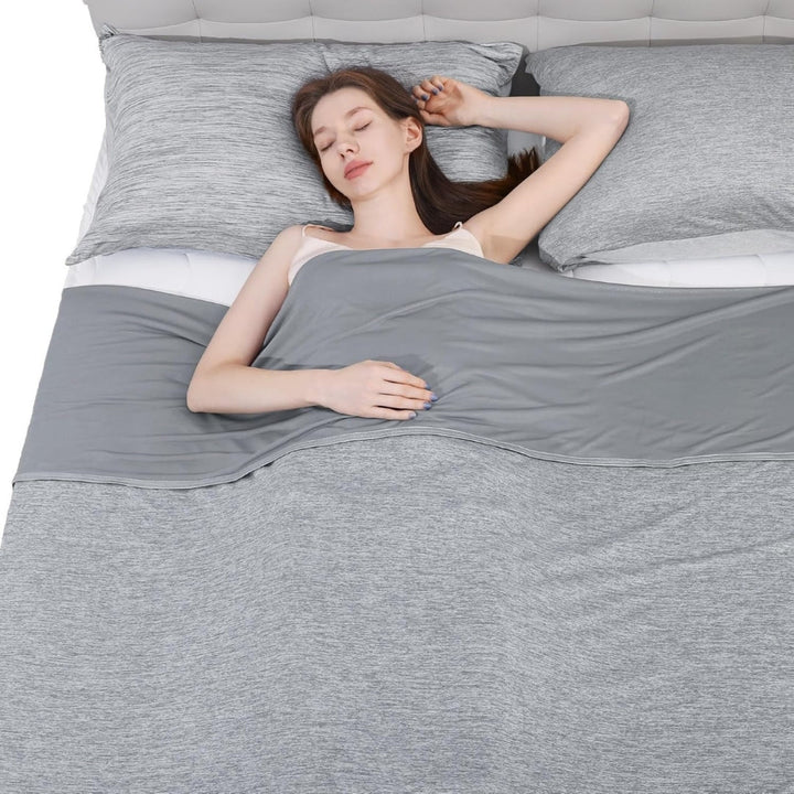 Kvinna som sover gott under en grå svalkande sommarfilt