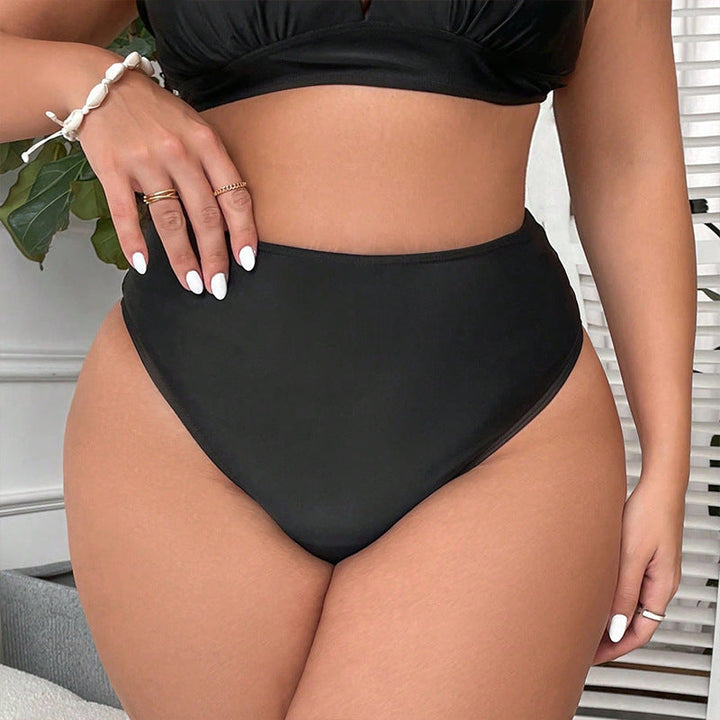 Moderiktig svart baddräktsunderdel med hög midja och asymmetriska cut-outs, elegant strandmode för kvinnor.