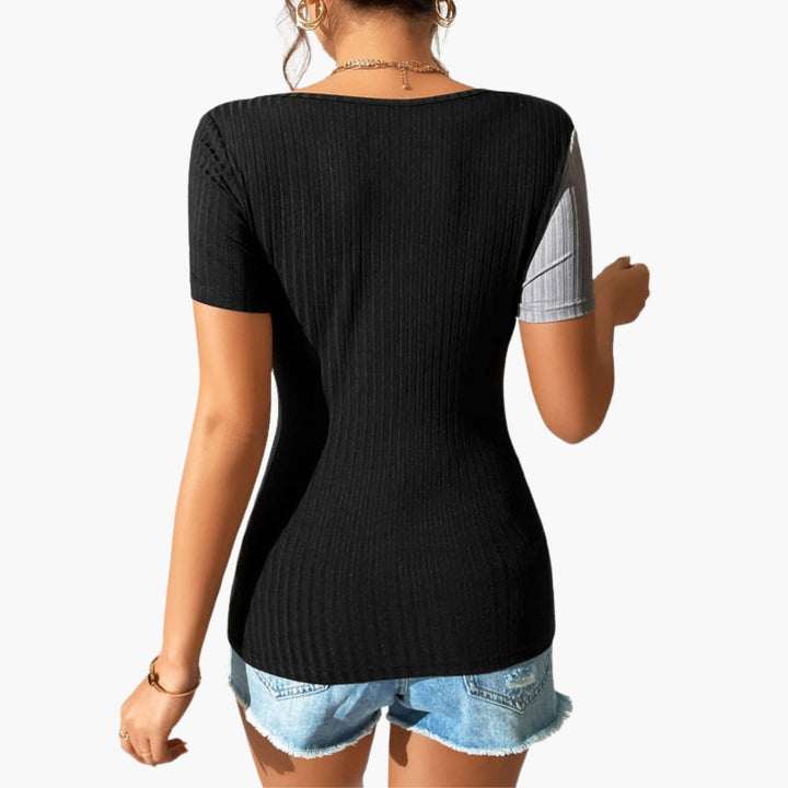 Modern svart dam t-shirt med asymmetrisk halsringning, kortärmad och med stilren bröstutskärning. Ribbad vardagstopp.