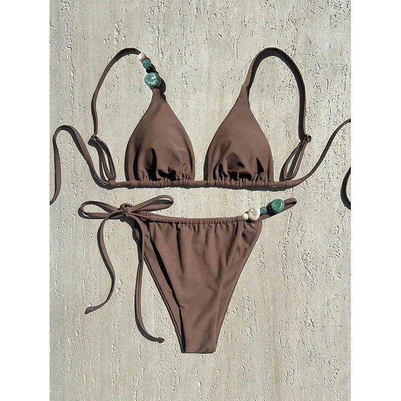 Modern damtriangelbikini i klassiskt svart, accentuerad med fina smyckesdetaljer för en chic look.