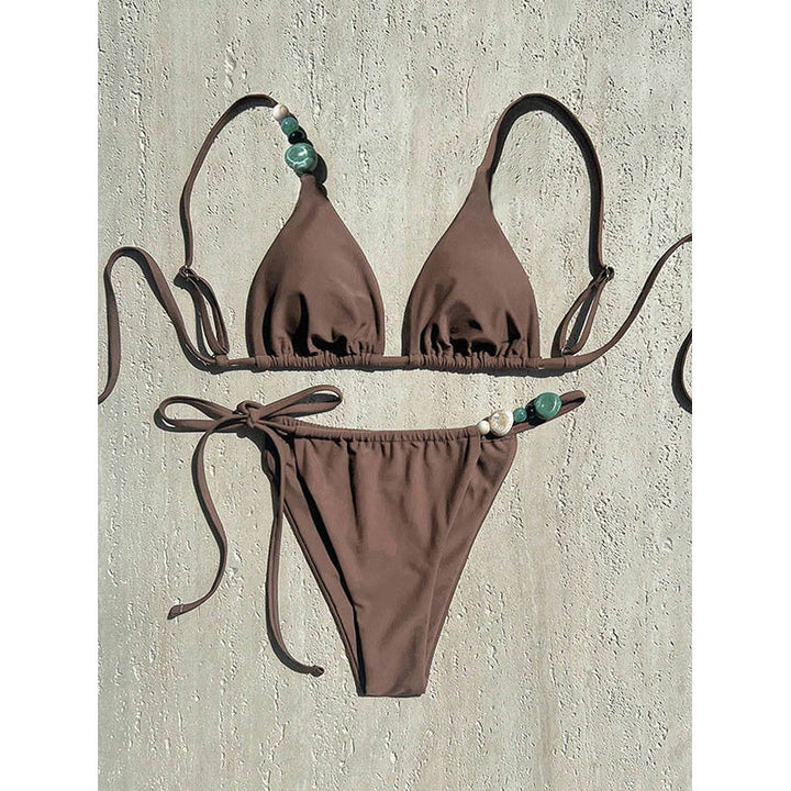 Modern damtriangelbikini i klassiskt svart, accentuerad med fina smyckesdetaljer för en chic look.
