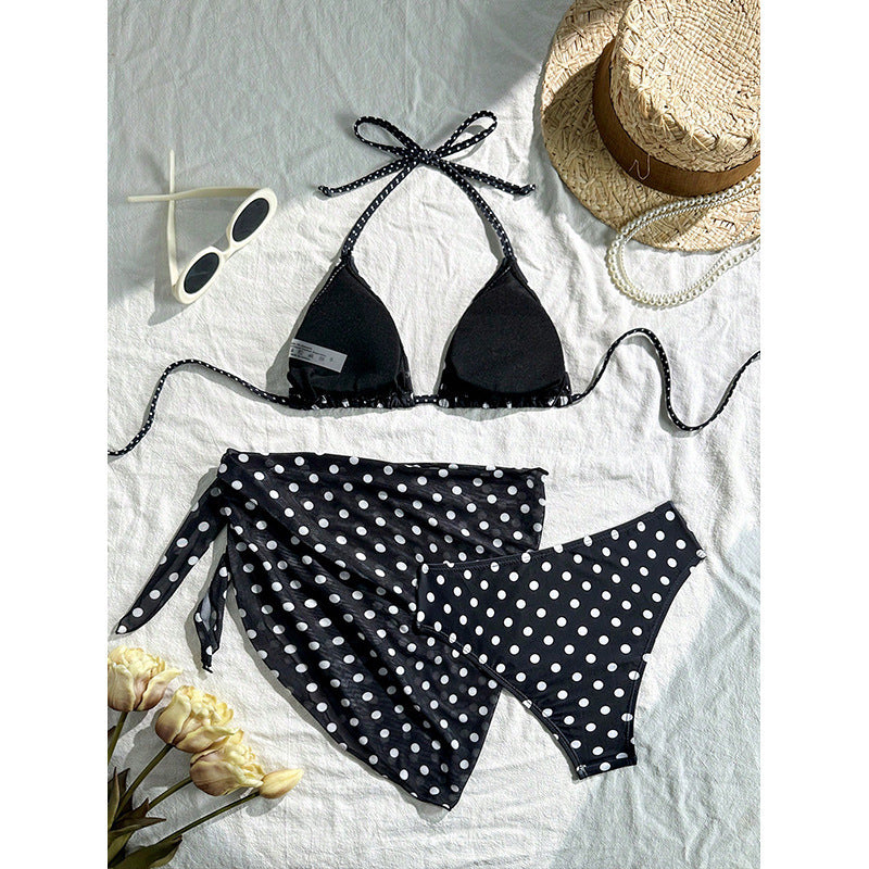 Svart bikinitrosa med vita prickar, del av ett prickigt badkläder-set för dam. Bekväma sommarplagg.